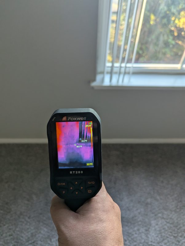 Foxwell RT280 held to a wall — moisture bloom in false color